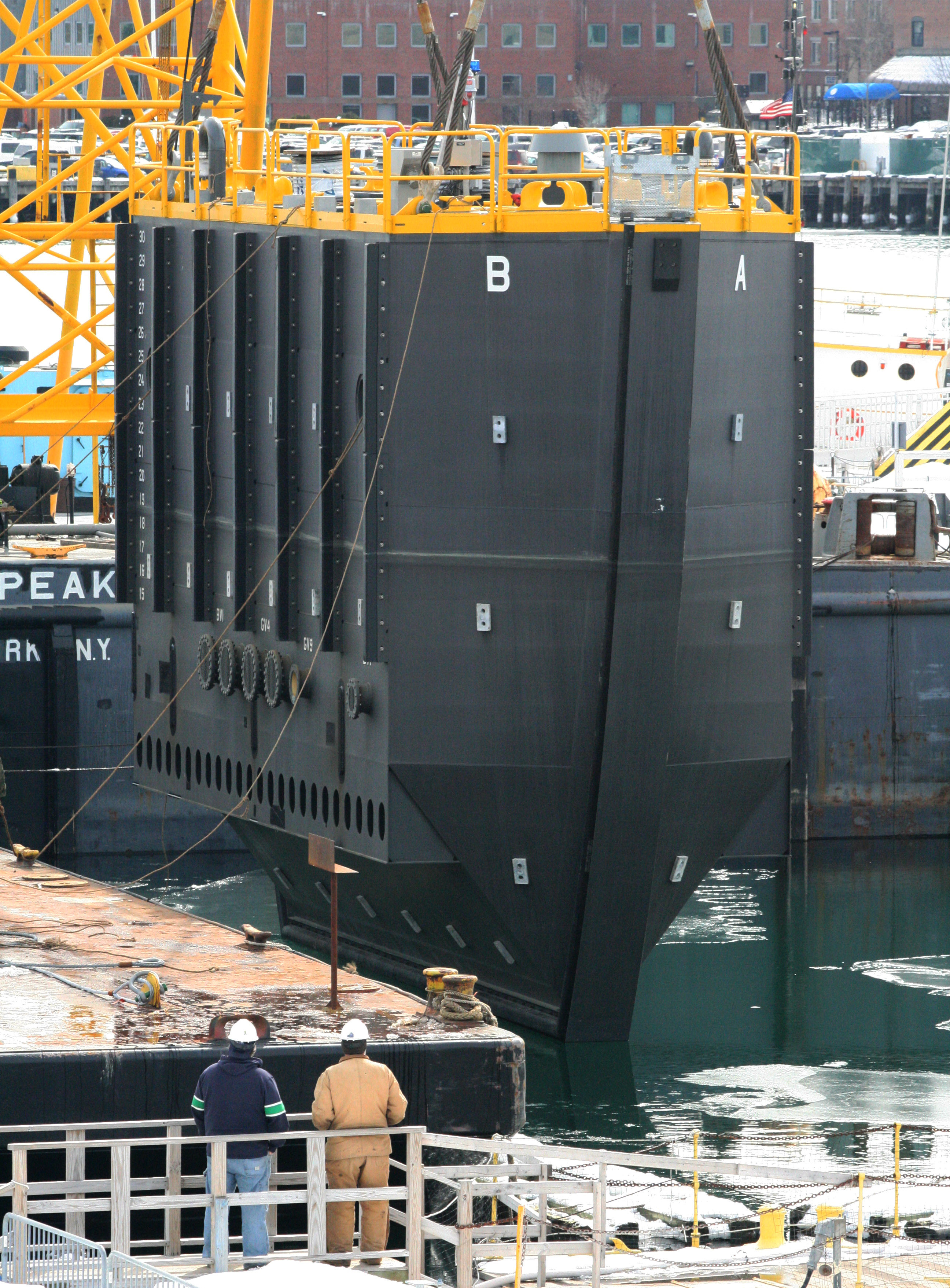 The new caisson is lifted from the barge and placed into Boston Harbor, March 2015. [Courtesy Naval History & Heritage Command Detachment Boston]