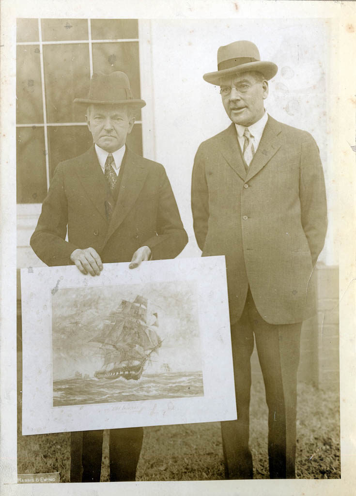 President Calvin Coolidge and Secretary of the Navy Wilbur hold a mounted lithograph of Gordan Grant's painting of USS Constitution, 1920s. [USS Constitution Museum Collection.]