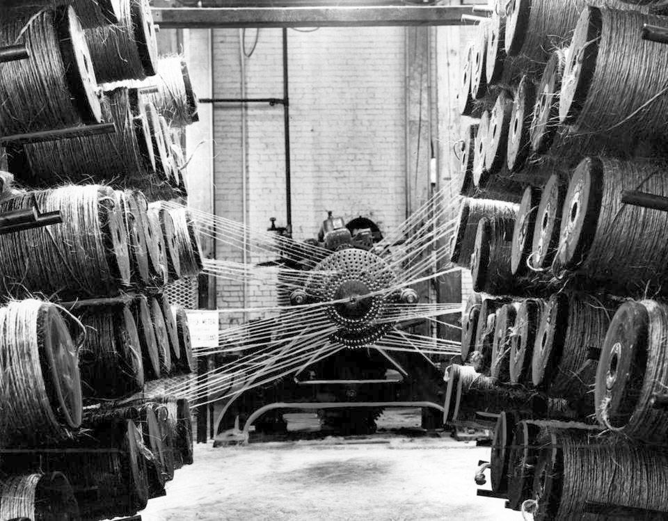 Yarns were fed into a machine and twisted together to make a single thread at the Ropewalk in Charlestown Navy Yard, 1955. [Courtesy of Boston Globe]