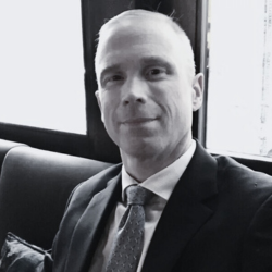 Headshot of man in dark suit jacket with tie