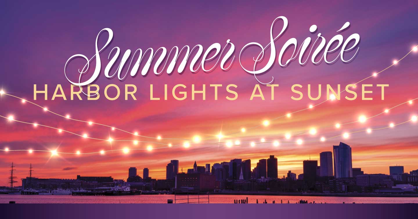 Boston city skyline against the harbor at sunset with an illuminating string of lights